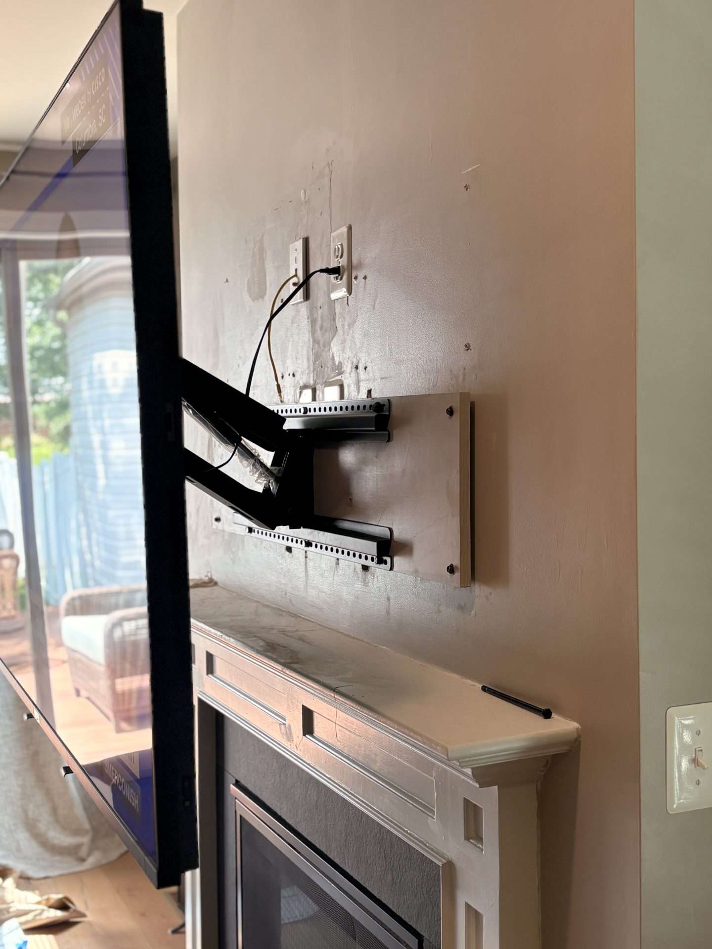Pull down television mount showing relocated outlet and low voltage connection behind TV