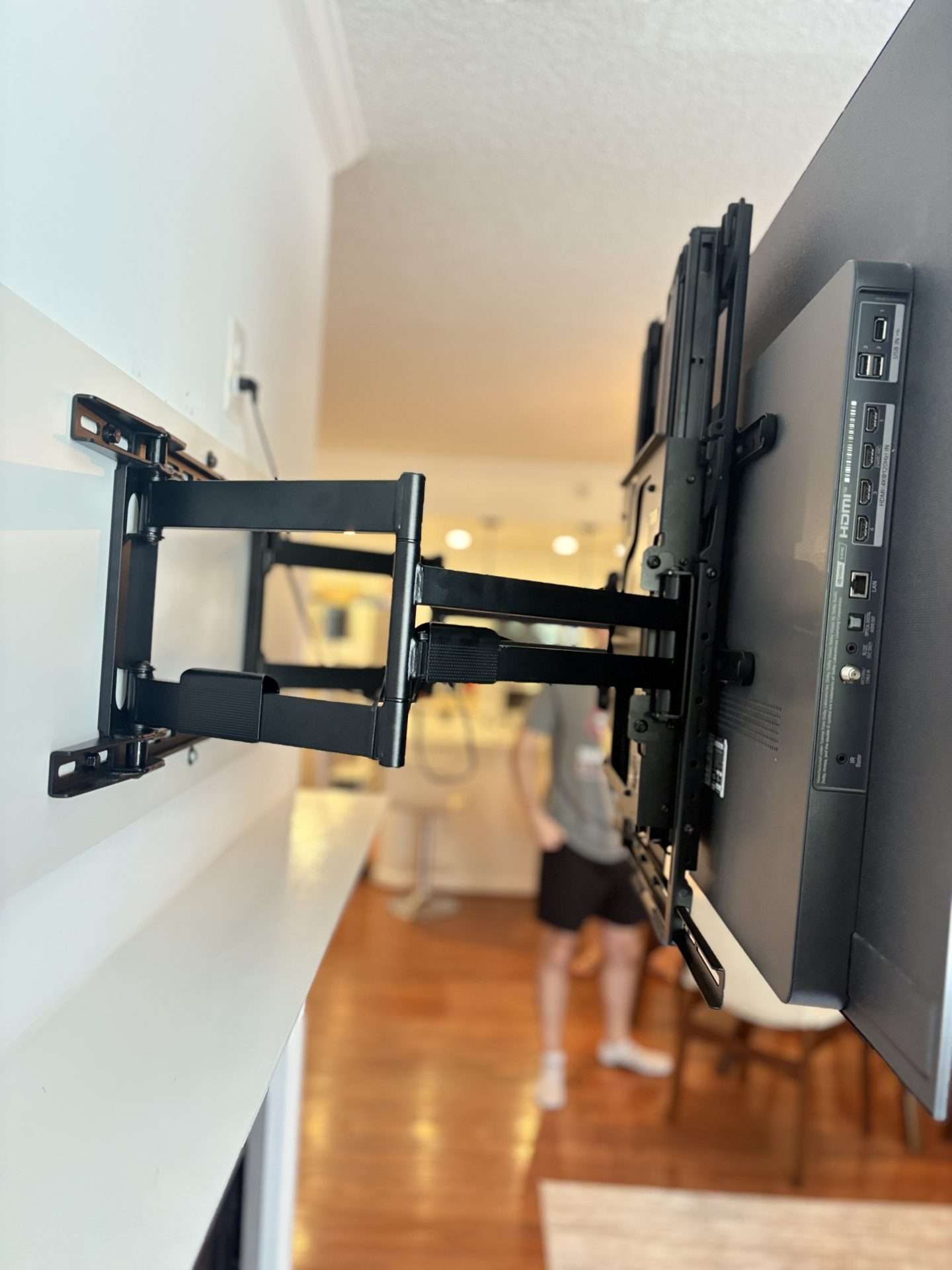 Pull-down TV mount installed over custom wood backing on fireplace wall