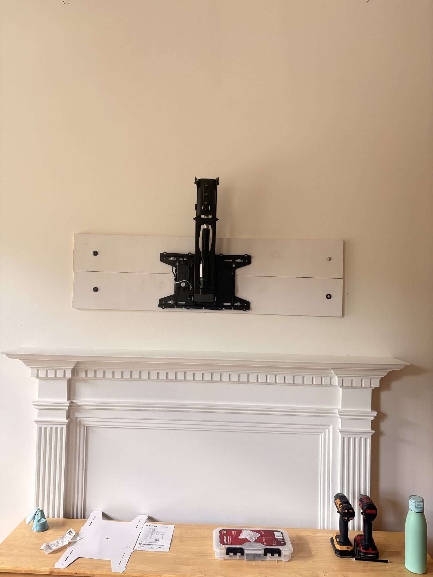 Custom wood backing and TV mount installed above fireplace
